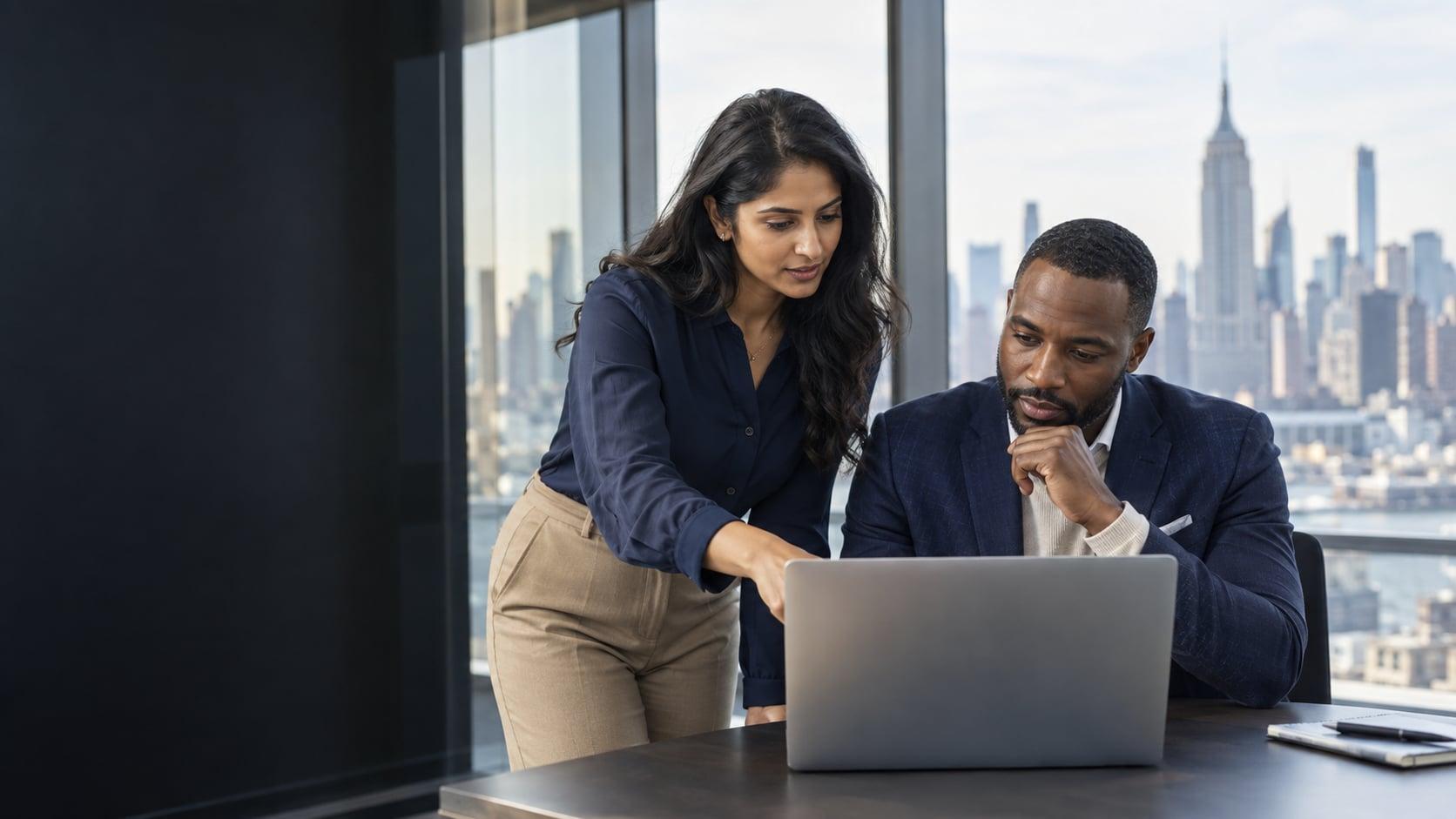 Colleagues reviewing work together on a laptop